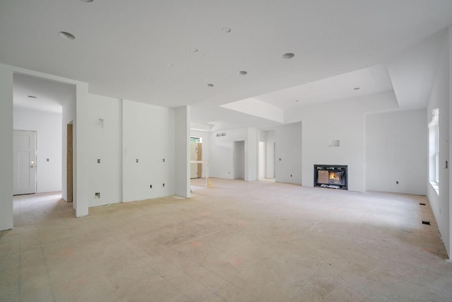 LT3 E Miramar Dr, East Troy, WI 53120 - unfurnished living room featuring a glass covered fireplace, a tray ceiling, and light carpet