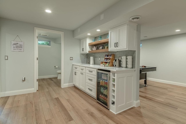 3472 Hickory Hill Rd, Verona, WI 53593 - indoor wet bar with beverage cooler, light wood-style floors, recessed lighting, and decorative backsplash