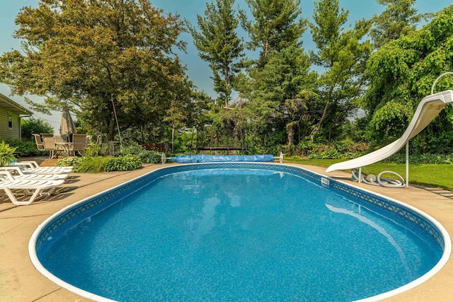 3472 Hickory Hill Rd, Verona, WI 53593 - view of swimming pool featuring a water slide, a patio area, a covered pool, and view of wooded area