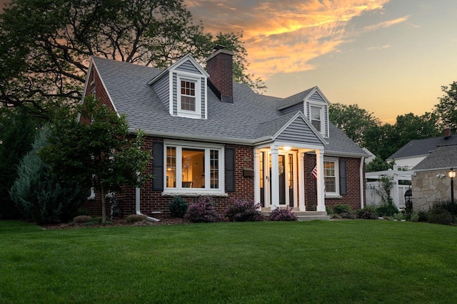 2461 N 94th St, Wauwatosa, WI 53226 - cape cod-style house with brick siding, a chimney, a front lawn, and a shingled roof