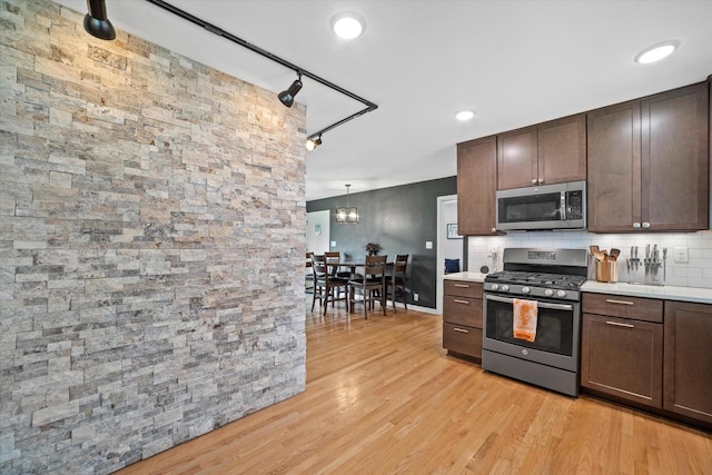 3351 W Vogel Ave, Greenfield, WI 53221 - kitchen with stainless steel appliances, light countertops, dark brown cabinetry, light wood finished floors, and decorative backsplash