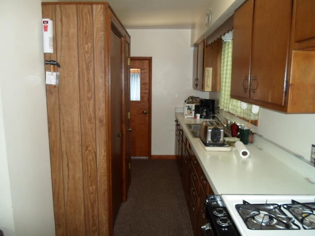 212 E Bowen St, Brandon, WI 53919 - kitchen with light countertops, brown cabinetry, dark colored carpet, and range with gas cooktop