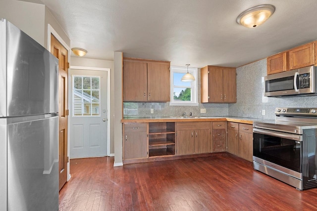 2717 13th St, Two Rivers, WI 54241 - kitchen featuring appliances with stainless steel finishes, dark wood-style floors, light countertops, decorative backsplash, and pendant lighting