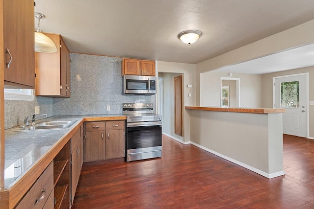 2717 13th St, Two Rivers, WI 54241 - kitchen featuring appliances with stainless steel finishes, dark wood-style flooring, backsplash, brown cabinetry, and a peninsula