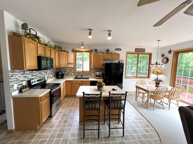 2783 High Peak Rd, Rhinelander, WI 54501 - kitchen featuring black appliances, light countertops, decorative backsplash, a kitchen island, and a breakfast bar area