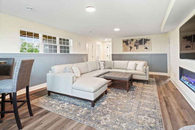 1386 Overlook Cir, Hartland, WI 53029 - living area with a glass covered fireplace, wood finished floors, a wainscoted wall, a decorative wall, and recessed lighting