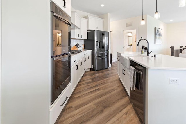 1386 Overlook Cir, Hartland, WI 53029 - kitchen featuring appliances with stainless steel finishes, decorative backsplash, dark wood-style floors, light countertops, and a center island with sink