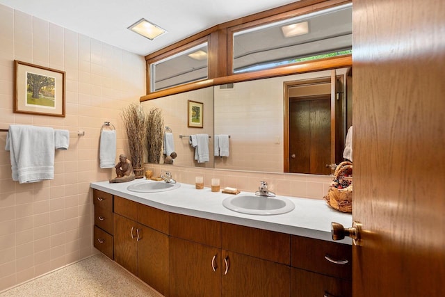 1225 W Cedar St, Appleton, WI 54914 - bathroom featuring speckled floor, double vanity, tile walls, and decorative backsplash