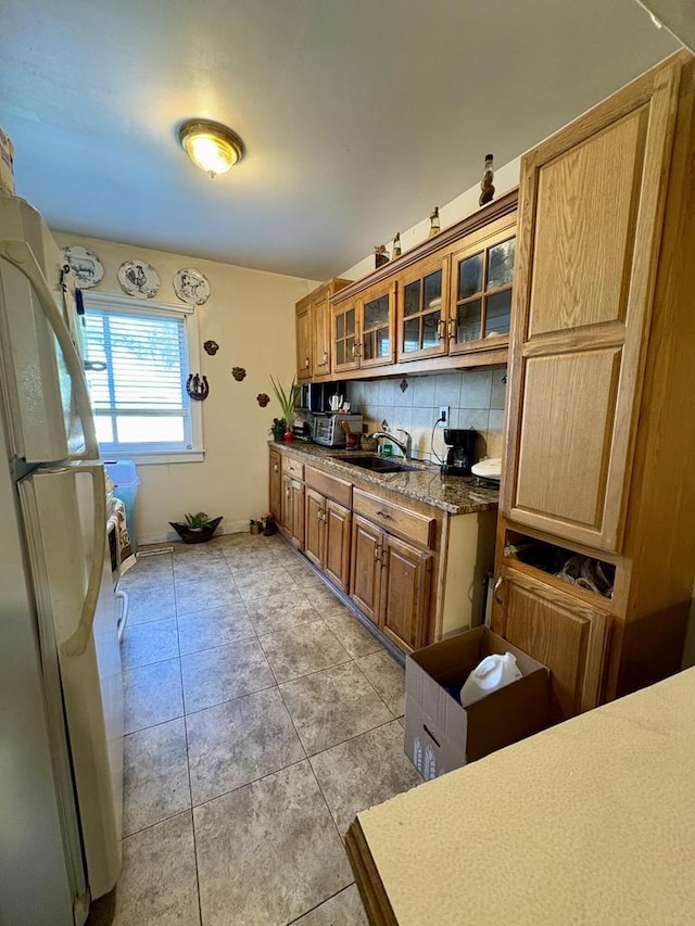 4110 N 7th St, Milwaukee, WI 53209 - kitchen with freestanding refrigerator, decorative backsplash, brown cabinetry, glass insert cabinets, and light tile patterned floors