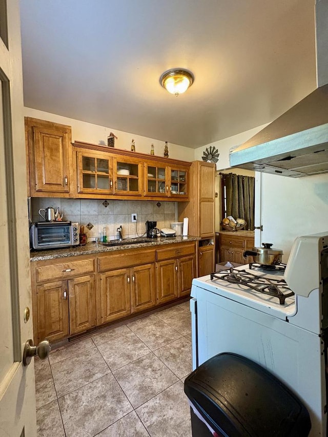 4110 N 7th St, Milwaukee, WI 53209 - kitchen featuring brown cabinetry, white range with gas stovetop, wall chimney exhaust hood, and light tile patterned floors
