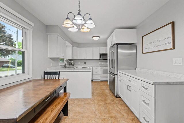 931 W Lindbergh St, Appleton, WI 54914 - kitchen featuring stainless steel appliances, a chandelier, light countertops, white cabinets, and decorative light fixtures