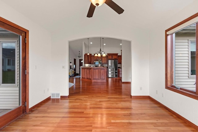 52 Penbrook Cir Unit 47, Appleton, WI 54911 - unfurnished living room featuring light wood-style flooring, a ceiling fan, a chandelier, arched walkways, and vaulted ceiling