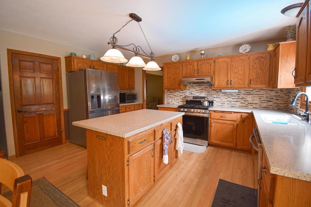 1135 W Walworth Ave, Whitewater, WI 53190 - kitchen with stainless steel appliances, under cabinet range hood, light wood-style flooring, a kitchen island, and backsplash