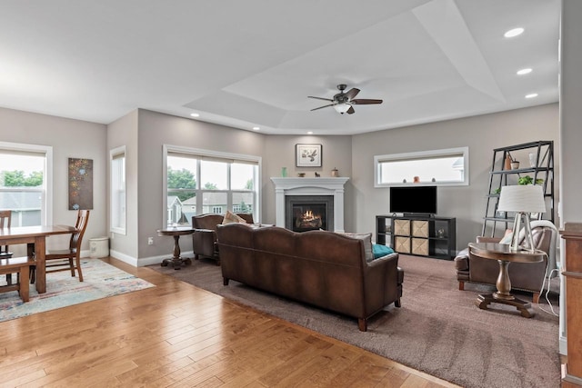 4790 Innovation Dr, Deforest, WI 53532 - living room with a raised ceiling, a ceiling fan, wood-type flooring, recessed lighting, and a warm lit fireplace