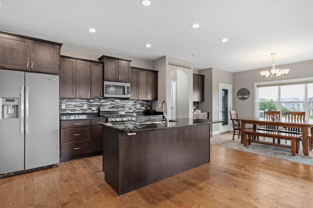 4790 Innovation Dr, Deforest, WI 53532 - kitchen featuring appliances with stainless steel finishes, dark brown cabinetry, light wood-style floors, a chandelier, and tasteful backsplash