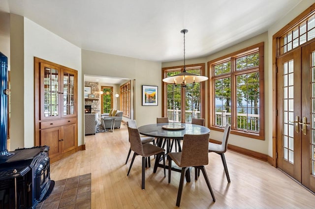 1124 Garrett Bay Rd, Ellison Bay, WI 54210 - dining area with french doors, light wood-type flooring, a fireplace, and a chandelier