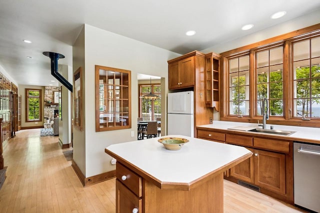 1124 Garrett Bay Rd, Ellison Bay, WI 54210 - kitchen with freestanding refrigerator, stainless steel dishwasher, light countertops, a center island, and brown cabinetry