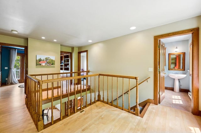 1124 Garrett Bay Rd, Ellison Bay, WI 54210 - hall with an upstairs landing, wood finished floors, recessed lighting, and a baseboard heating unit