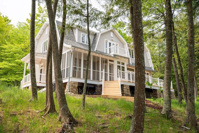 1124 Garrett Bay Rd, Ellison Bay, WI 54210 - rear view of property featuring a sunroom, a gambrel roof, stone siding, stairs, and a shingled roof