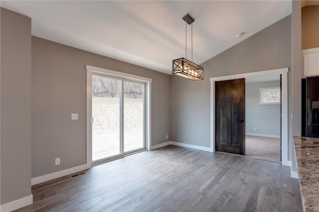 397 Candy Ln, River Falls, WI 54022 - empty room featuring a chandelier, wood finished floors, plenty of natural light, vaulted ceiling, and a smoke detector