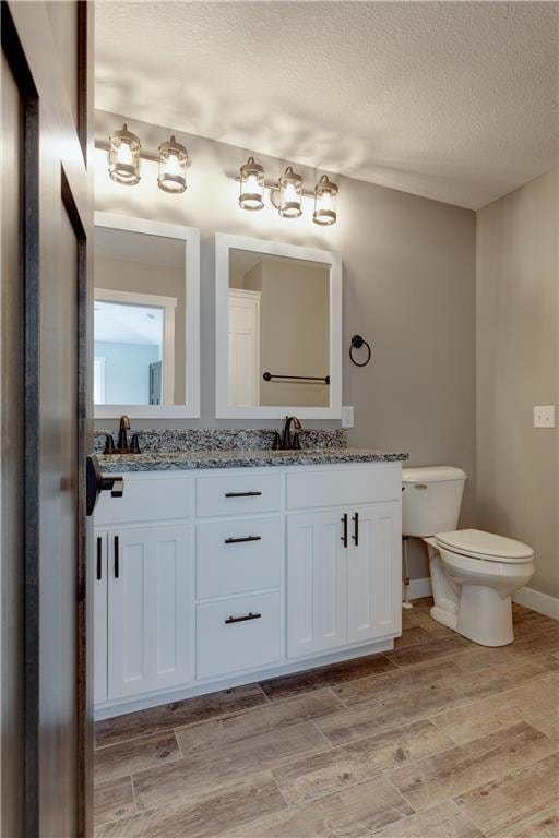 397 Candy Ln, River Falls, WI 54022 - bathroom featuring a textured ceiling, double vanity, and wood finished floors