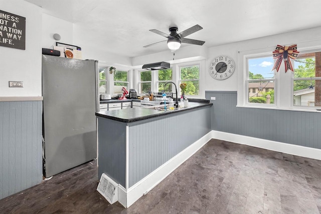 152 Hoyt St, Fond Du Lac, WI 54935 - kitchen with stainless steel appliances, dark countertops, ceiling fan, wainscoting, and wooden walls