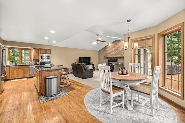 2621 Russet Dr, Plover, WI 54467 - dining room featuring ceiling fan, plenty of natural light, light wood finished floors, a brick fireplace, and lofted ceiling