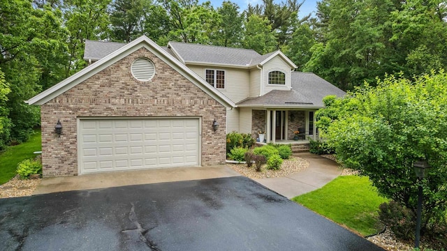 2621 Russet Dr, Plover, WI 54467 - traditional-style house featuring driveway, brick siding, covered porch, a garage, and a shingled roof