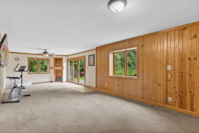 110 Chestnut Way, North Prairie, WI 53153 - unfurnished living room with crown molding, carpet floors, a ceiling fan, wood walls, and a textured ceiling