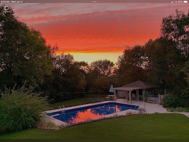 110 Chestnut Way, North Prairie, WI 53153 - pool at dusk with an exterior structure, a lawn, a patio area, an outbuilding, and an outdoor pool