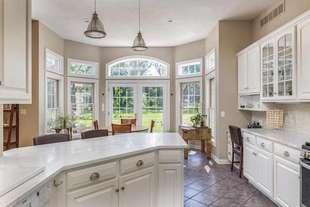 3864 Candlish Harbor Ln, Oshkosh, WI 54902 - kitchen featuring glass insert cabinets, white cabinetry, backsplash, pendant lighting, and light stone countertops