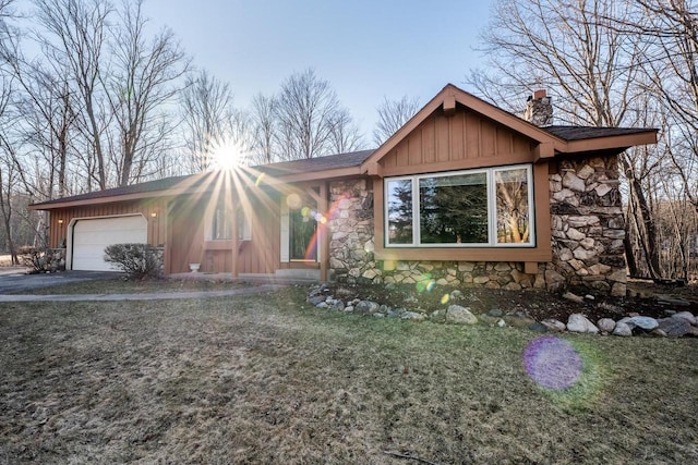 8420 Southview Dr, Crandon, WI 54520 - view of front of house with stone siding, a chimney, a garage, driveway, and board and batten siding
