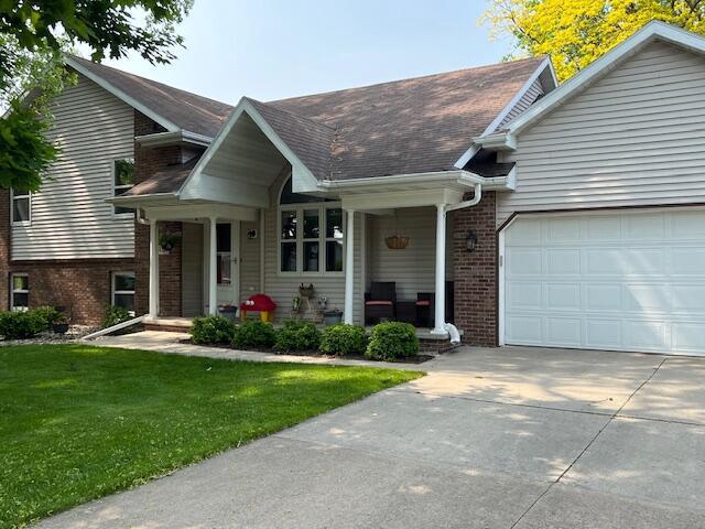 1434 Alcan Dr, Menasha, WI 54952 - view of front of property with an attached garage, brick siding, driveway, a front lawn, and a porch