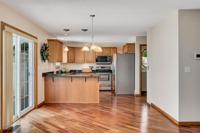 2641 13th Ct, La Crosse, WI 54601 - kitchen with appliances with stainless steel finishes, a peninsula, light wood finished floors, a kitchen bar, and recessed lighting