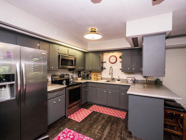 614 Decker Dr, West Bend, WI 53090 - kitchen featuring stainless steel appliances, dark wood finished floors, light countertops, a kitchen bar, and gray cabinets