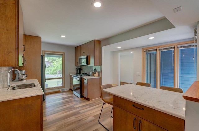 5043 Marathon Dr, Madison, WI 53705 - kitchen with appliances with stainless steel finishes, light wood-style flooring, tasteful backsplash, recessed lighting, and brown cabinets