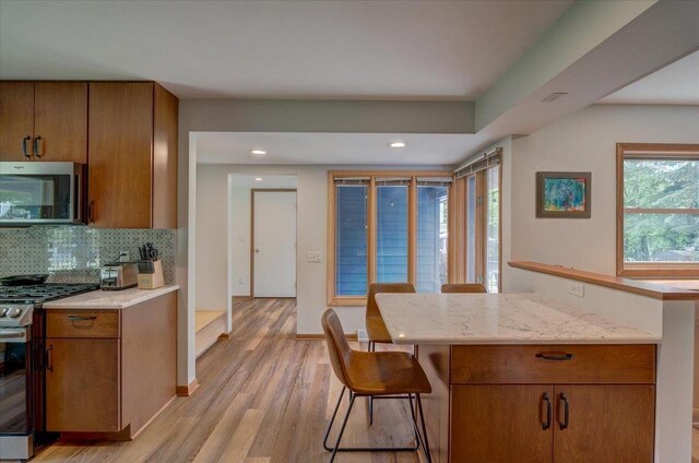 5043 Marathon Dr, Madison, WI 53705 - kitchen featuring appliances with stainless steel finishes, brown cabinets, backsplash, light wood-type flooring, and recessed lighting