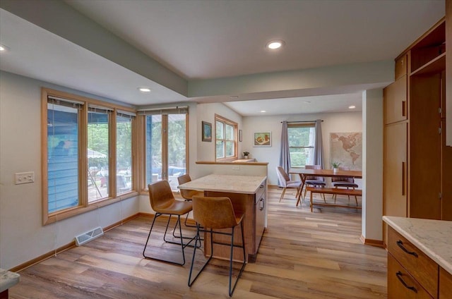 5043 Marathon Dr, Madison, WI 53705 - kitchen featuring light wood-style floors, recessed lighting, brown cabinetry, light stone countertops, and a breakfast bar