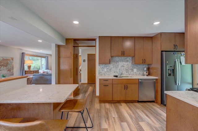 5043 Marathon Dr, Madison, WI 53705 - kitchen with stainless steel appliances, light wood-style flooring, tasteful backsplash, recessed lighting, and brown cabinetry