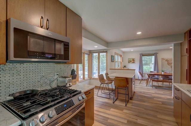 5043 Marathon Dr, Madison, WI 53705 - kitchen featuring stainless steel appliances, decorative backsplash, light wood-type flooring, a breakfast bar, and recessed lighting