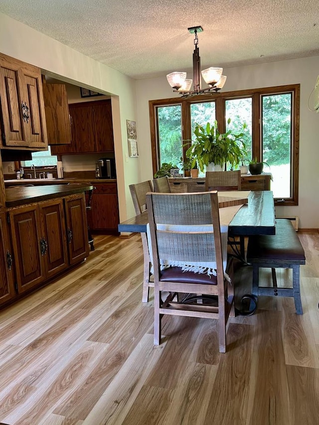 5116 S 84th St, Greendale, WI 53129 - dining area with light wood-style floors, a textured ceiling, plenty of natural light, and a chandelier