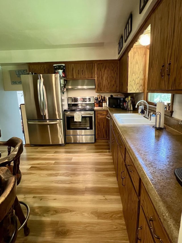 5116 S 84th St, Greendale, WI 53129 - kitchen with stainless steel appliances, extractor fan, light wood-style flooring, and brown cabinets