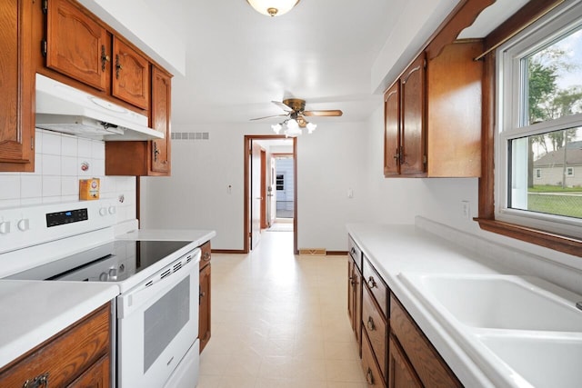 324 E Market St, Burlington, WI 53105 - kitchen featuring white electric range oven, under cabinet range hood, brown cabinets, light countertops, and light flooring