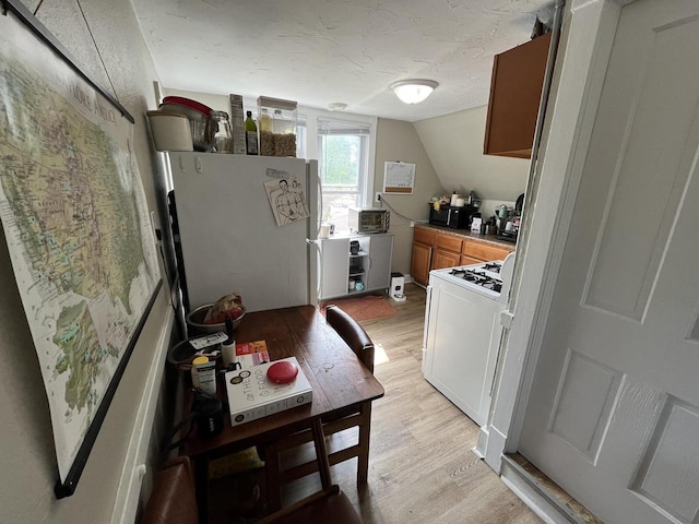 2928 N Humboldt Blvd Unit 2930, Milwaukee, WI 53212 - kitchen featuring white appliances, light wood finished floors, brown cabinets, lofted ceiling, and a textured ceiling