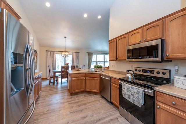 431 Thurow Dr, Oconomowoc, WI 53066 - kitchen featuring stainless steel appliances, a peninsula, brown cabinets, vaulted ceiling, and recessed lighting