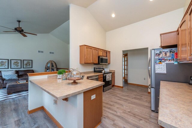 431 Thurow Dr, Oconomowoc, WI 53066 - kitchen featuring stainless steel appliances, a peninsula, high vaulted ceiling, ceiling fan, and light countertops