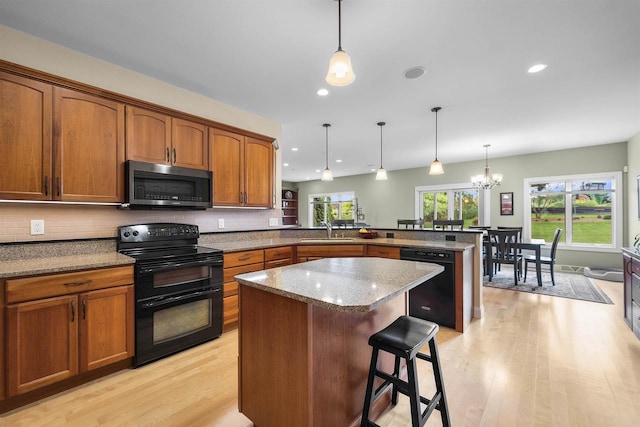 7131 Caneel Trl, Middleton, WI 53562 - kitchen featuring black appliances, a peninsula, light wood-type flooring, brown cabinets, and a kitchen island