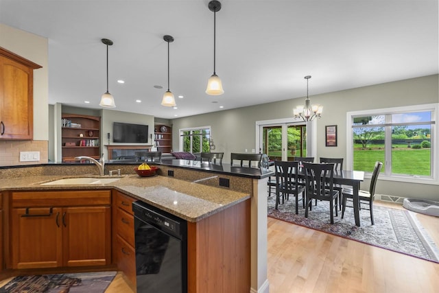 7131 Caneel Trl, Middleton, WI 53562 - kitchen featuring dishwasher, brown cabinetry, dark stone counters, open floor plan, and light wood-type flooring