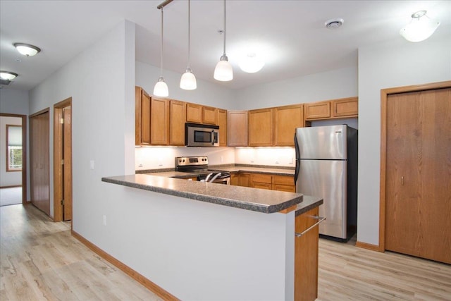 6701 Fairhaven Rd Unit 202, Madison, WI 53719 - kitchen with appliances with stainless steel finishes, light wood-style floors, a peninsula, dark countertops, and decorative light fixtures