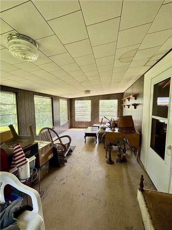 306 Pleasant Ave, Frederic, WI 54837 - living room featuring plenty of natural light, unfinished concrete flooring, and wooden walls